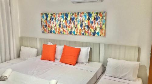 a bedroom with a bed with orange and white pillows at Arraial d Ajuda - Casa Oásis - Residencial Monte das Oliveiras in Porto Seguro