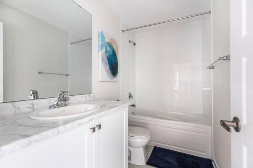 La salle de bains blanche est pourvue d'un lavabo et de toilettes. dans l'établissement Modern 3BR, 15min to Falls/Attractions W/ King Bed, à Thorold