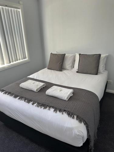 a large white bed with two pillows on it at Mudgee Riverside Park in Mudgee