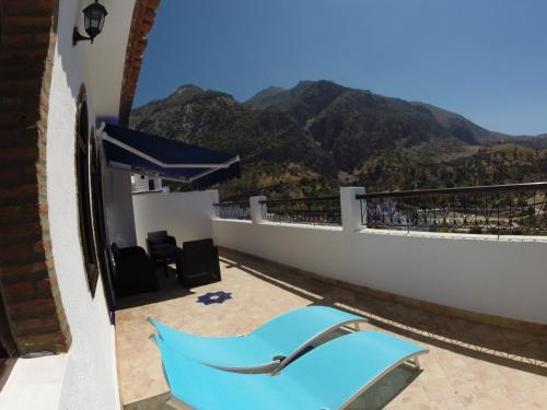 a blue chair on a balcony with mountains in the background at Riad Zaitouna Chaouen in Chefchaouene
