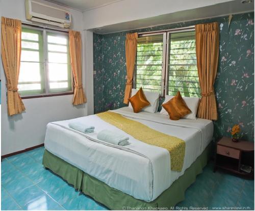 um quarto com uma cama grande e 2 janelas em Huaykhakhaeng Country Home Resort em Ban Rai