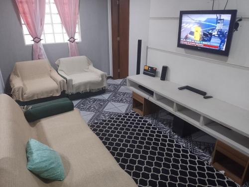 a living room with a tv and a couch and chairs at LINDA CASA DE PRAIA EM PIRATININGA in Niterói
