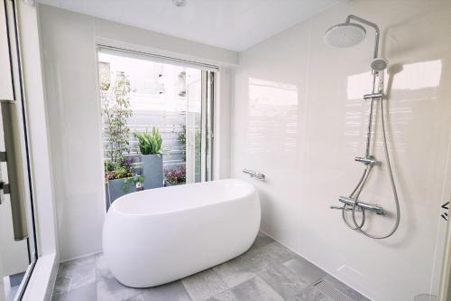 a white bathroom with a tub and a toilet at 「まちのオアシス」STAY UWU 005 空を眺める半露天風呂 in Kochi