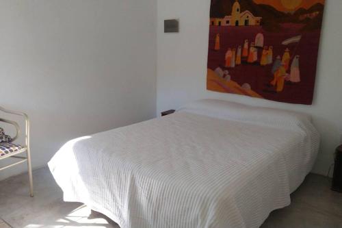 維拉阿連德的住宿－La casita anaranjá，卧室配有一张白色床,墙上挂有绘画作品