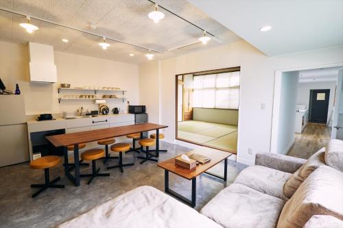 un soggiorno con un tavolo e un divano di 「まちのオアシス」STAY UWU 005 空を眺める半露天風呂 a Kochi