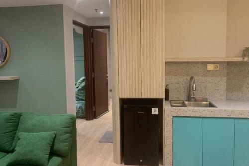 - une cuisine avec un canapé vert dans une chambre dans l'établissement 2BR+, Apartement Sudirman Bandung, à Bandung
