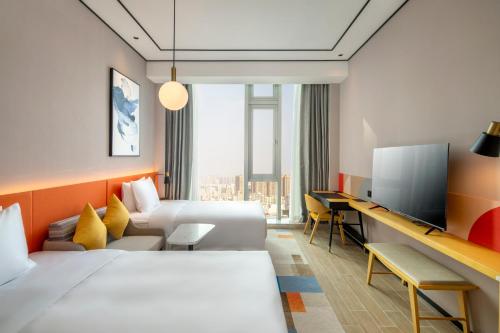 a hotel room with two beds and a flat screen tv at Hilton Garden Inn Shenzhen Airport,Enjoy 24-hour one way free delivery from hotel to Shenzhen Baoan Airport on the hour in Shenzhen