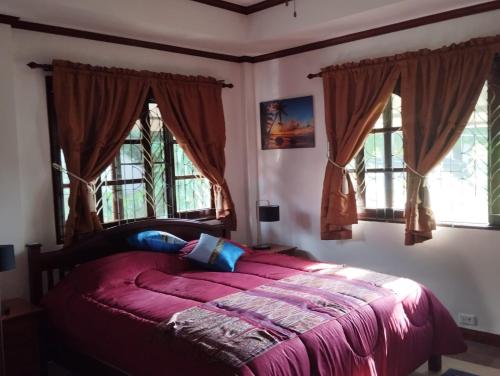 Un dormitorio con una cama con sábanas y ventanas púrpuras. en Le Paradis sur Kos Samui,bang po plage, en Ban Bang Po