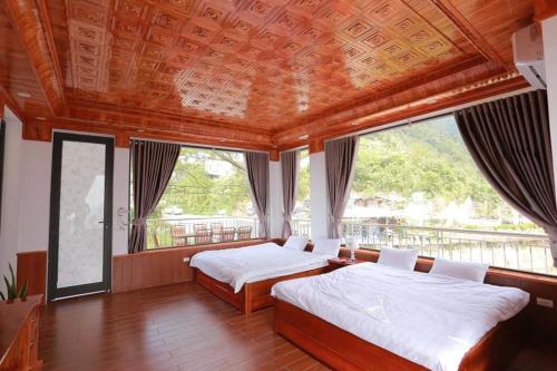 a bedroom with two beds and a large window at Ruby Tam Đảo in Tam Ðảo
