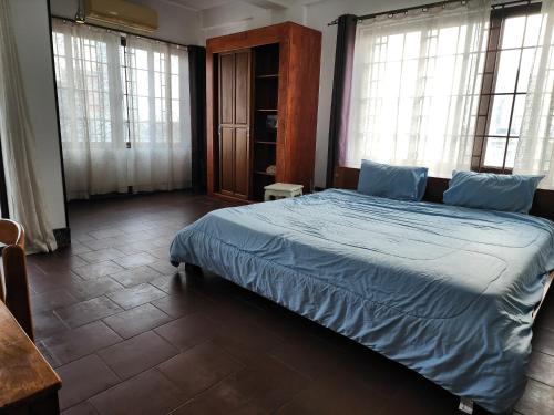 um quarto com uma cama com lençóis azuis e janelas em CHILCHILL Elite Residences BKK2 em Phnom Penh