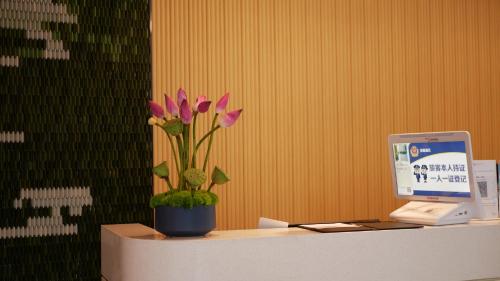 a desk with a computer and a potted plant on it at Hilton Garden Inn Shenzhen Airport,Enjoy 24-hour one way free delivery from hotel to Shenzhen Baoan Airport on the hour in Shenzhen