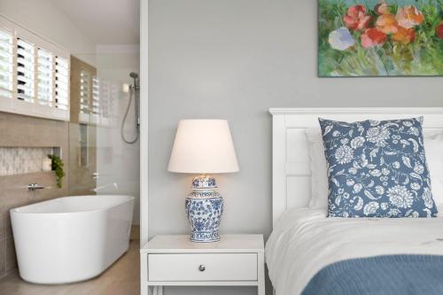 a bedroom with a bed and a lamp and a bath tub at 153 Centenary Heights Rd in Yaroomba