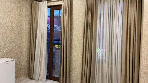 um quarto com cortinas e uma porta de vidro em Astoria Hotel em Zugdidi