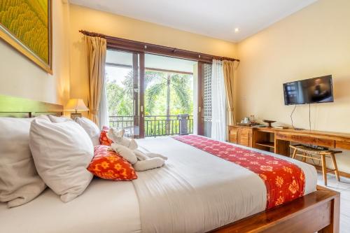 a bedroom with a bed and a desk and a television at Meruhdani Boutique Hotel Ubud in Ubud