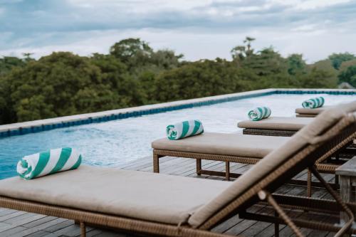 a row of lounge chairs next to a swimming pool at ARTOTEL Sanur Bali in Sanur