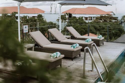 three lounge chairs and an umbrella on a deck at ARTOTEL Sanur Bali in Sanur