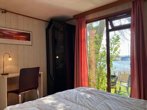 1 dormitorio con cama y ventana grande en Tolles 2 Pers Haus König mit Hafenblick am Lauwersmeer, en Anjum
