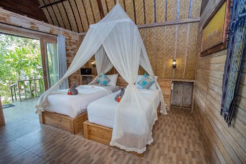 - une chambre avec 2 lits et des moustiquaires dans l'établissement Desa Sweet Cottages, à Nusa Lembongan