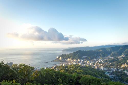uma vista para uma cidade e para o oceano a partir de uma colina em Hotel Grand Bach Atami Crescendo em Atami
