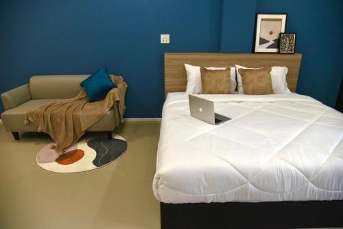 a bedroom with a bed and a couch with a laptop on it at HAKKA Wellness Residence in Samut Songkhram