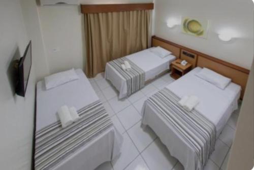 Cette chambre comprend deux lits et une télévision. dans l'établissement Alojamentos Rio Verde, à Rio Verde