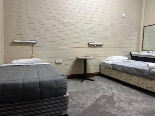 a room with two beds and a table in it at Club Hotel in Glen Innes