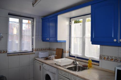 a kitchen with blue cabinets and a sink at Andar com jardim e estacionamento in Paço de Arcos