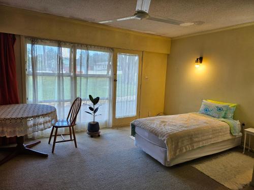a bedroom with a bed and a table and window at Park Lodge Motel in Te Awamutu