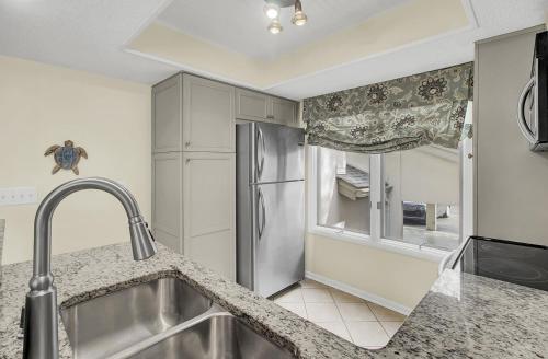 uma cozinha com um frigorífico de aço inoxidável e uma janela em 401 Yacht by AvantStay Marina View Pool Porch em Isle of Palms