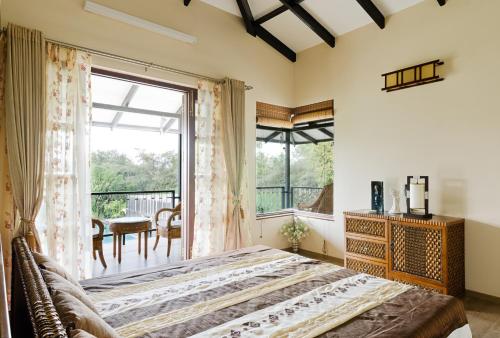 a bedroom with a bed and a large window at amã Stays & Trails Butterfly Villa, Deolali, Nashik in Nashik
