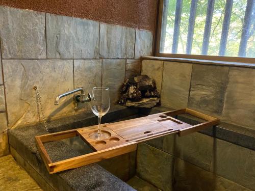 a wine glass sitting on a wooden tray in a bath tub at 準天然光明石溫泉キャビン アウトドアBbQタイム 映画の夜 邂逅 in Ashinoyu