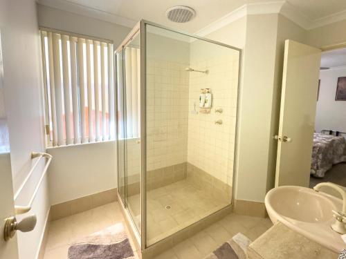 a bathroom with a glass shower and a sink at Ascot on Swan Bed & Breakfast in Perth