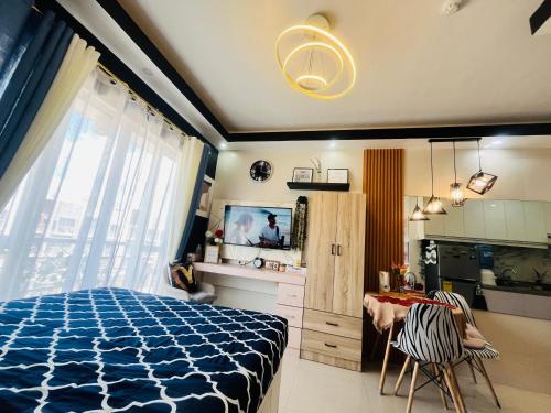 a bedroom with a blue bed and a kitchen at Azehr's Walk Up and Cozy Condo in Minglanilla