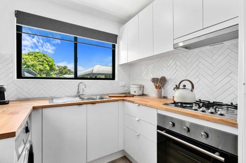 cocina blanca con fregadero y ventana en Faraway Retreat, en Urangan