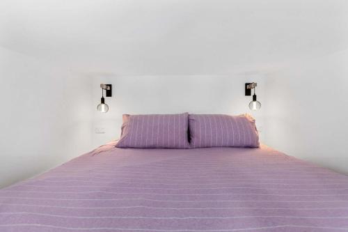Una cama púrpura con dos luces encima. en Faraway Retreat, en Urangan