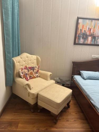 a bedroom with a chair with a pillow and a ottoman at Singh villa in Mohali