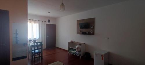 een woonkamer met een tafel en een tv aan de muur bij Hospedaria Caminho da Roça in Gonçalves