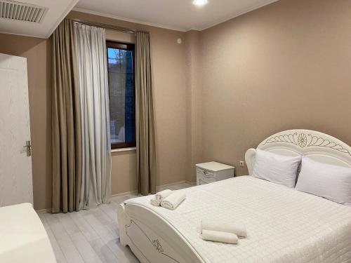 1 dormitorio con cama blanca y ventana en Astoria Hotel en Zugdidi