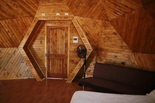 Habitación con techo de madera, puerta y sofá. en Domo en Viña Sanroke, en Río Claro