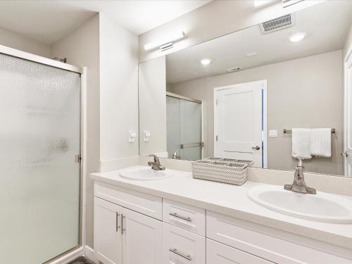 a white bathroom with two sinks and a shower at Exquisite Lakefront Condo in Sparks