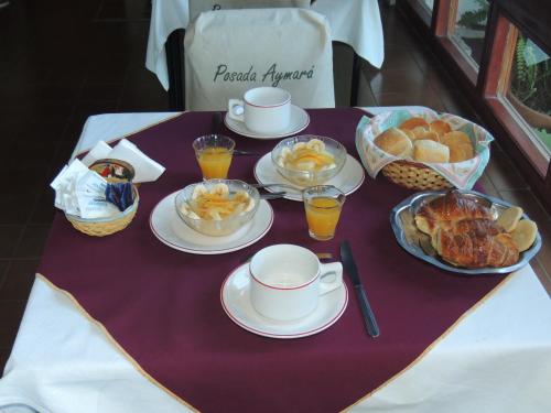 ein Tisch mit Tellern mit Essen und Tassen und Körben mit Brot in der Unterkunft Posada Aymara in La Falda