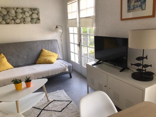 sala de estar con sofá y TV de pantalla plana en La Gardinière, en La Barre-de-Monts
