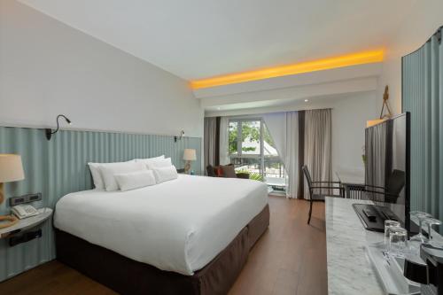 Habitación de hotel con cama grande y escritorio. en The Boathouse Phuket - SHA Plus, en Kata Beach