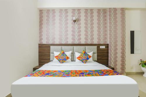 a bedroom with a large white bed with colorful pillows at FabHotel Corporate Stay in Noida