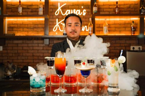a man behind a bar with a bunch of drinks at Hotel Maenamla Namchi - yagi group in Namchi