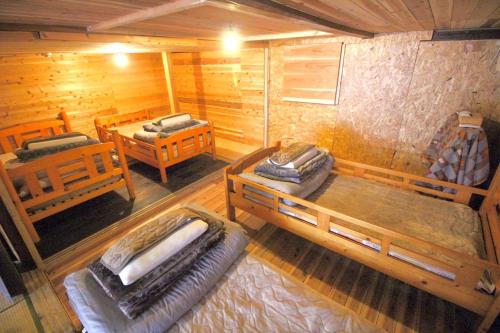Habitación con 3 camas en una cabaña de madera en まるもりホステル en Wada