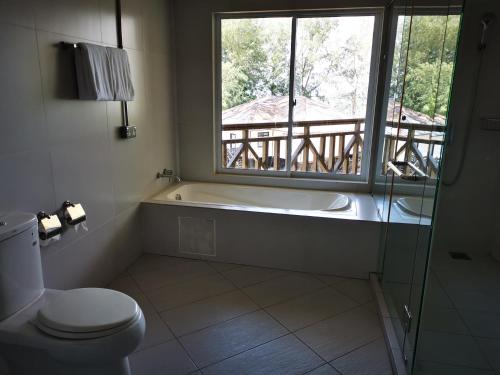 a bathroom with a tub and a toilet and a window at Century Langkasuka Resort Langkawi in Pantai Cenang