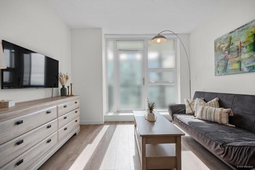 a living room with a black couch and a tv at Stylish and Tranquil Retreat in Richmond City Center in Richmond