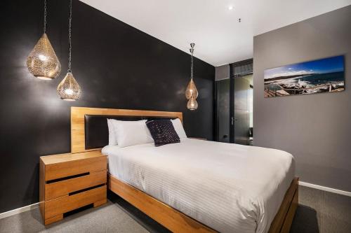 1 dormitorio con 1 cama y 2 luces colgantes en Sky High Views in the Heart of Canberra, en Canberra
