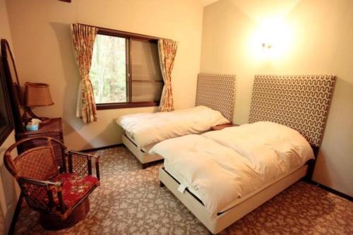 a bedroom with two beds and a window at 箱根温泉ヴィラ 源泉かけ流し bbq付き グループ宿泊に最適 in Hakone